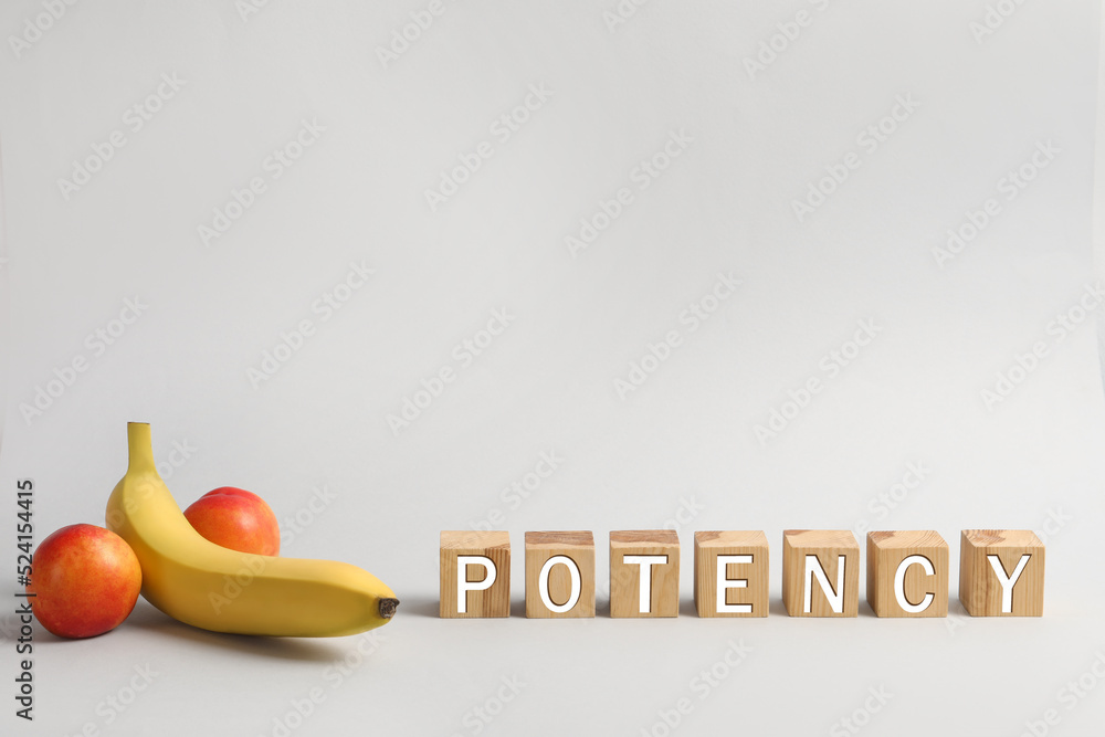 Wall mural Cubes with word Potency near banana and nectarines symbolizing male genitals on light grey background, space for text