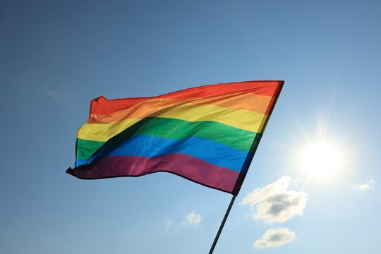 Bright LGBT flag fluttering against blue sky. Lesbian concept