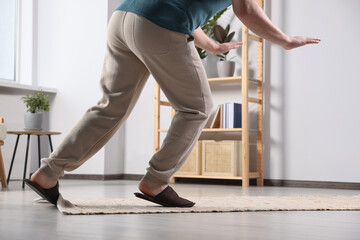 Man tripping over rug at home, closeup - obrazy, fototapety, plakaty