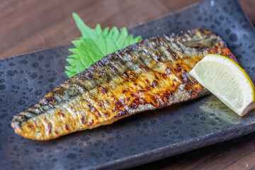 和食レストランや居酒屋で提供される、脂ののったサバの干物焼き。こんがりと黄金色に焼き上げ、レモンと大葉を添えたシズル感あふれる一品料理。テキストを入れるスペースあり