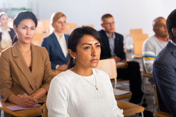 Portrait of focused Latina attending business conference, listening with interest to speaker