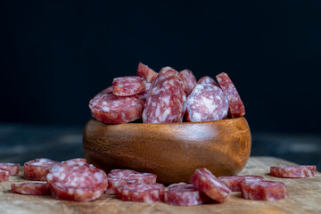 sliced thin sausage with bacon on a wooden dish