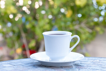 Close up a white coffee cup  and  saucer on the table  in the yard.