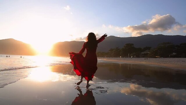Beach scene at sunset with woman in red dress dancing flamenco. Gimbal