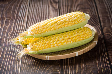 Fresh ripe yellow cobs corn on wooden table