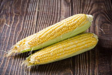 Fresh ripe yellow cobs corn on wooden table