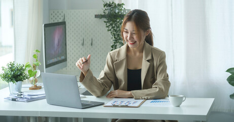 Charming young businesswoman sitting in bright office and working with modern devices.
