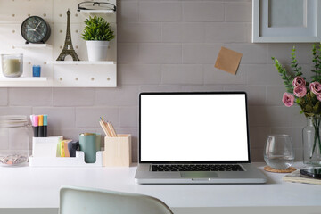 Front view computer laptop with empty display, books and potted plant on white table.