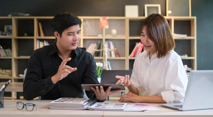 Two young creative designer discussing for their new project together in office.