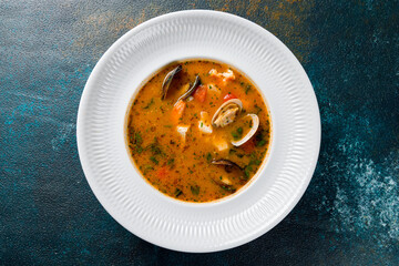 Marseille fish soup with seafood on white plate on dark blue table top view
