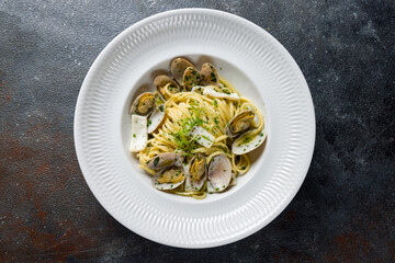 Linguini with vongole in wine sauce on white plate top view