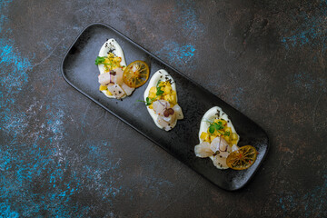 Sashimi scallop on a plate with sauce and mando and orange chips top view