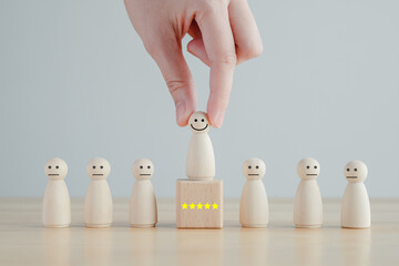 Hand pick happy face wooden figure. Customer service rating experience and feedback emotion and satisfaction survey. Human Resources management choosing positive attitude to team.