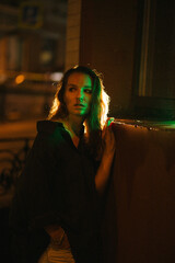 A girl walks around the city at night after the rain among the light of lanterns and cars