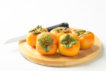 Ripe persimmon fruit on cutting wooden board with knife prepare for cooking