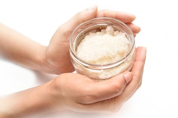 A girl Holding a bottle of cosmetic. The scrub is made out of cane sugar and sea sault. 