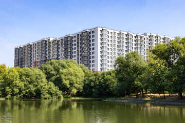 Fototapeta premium New modern residential apartment building near the lake surrounded by green trees 