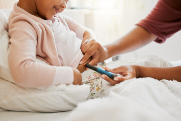 Obraz na płótnie Canvas Testing glucose, blood pressure and diabetes of little girl with insulin treatment in bed at home. Mother checking health, wellness and blood sugar medical measurement of her daughter in a bedroom