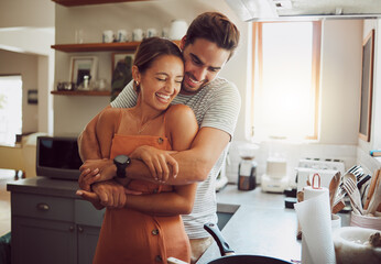 Love, romance and fun couple hugging, cooking in a kitchen and sharing an intimate moment. Romantic boyfriend and girlfriend embracing, enjoying their relationship and being carefree together - obrazy, fototapety, plakaty