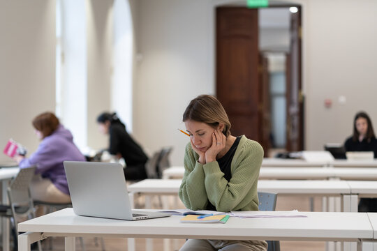 Sad middle-aged female student trying to concentrate on doing homework, getting new qualification, gaining new skills in middle age, mature woman adult learner feeling bored and tired of online study