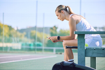 Fit tennis player with phone checking fitness goal progress on a sports exercise app online while...