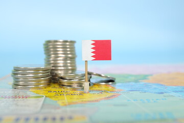 Selective focus of Bahraini flag in blurry world map with coins. Bahrain economy and wealth concept.