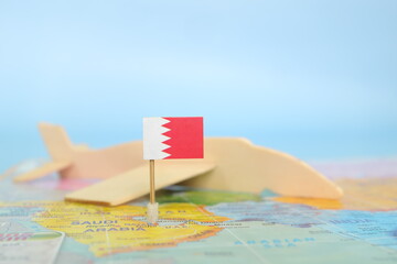 Selective focus of Bahraini flag in blurry world map and wooden airplane model. Bahrain as travel...
