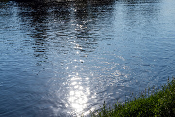 Sun glare in the water of the river with waves