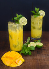 Mango mojito in highball glass with sliced mango isolated on wooden table