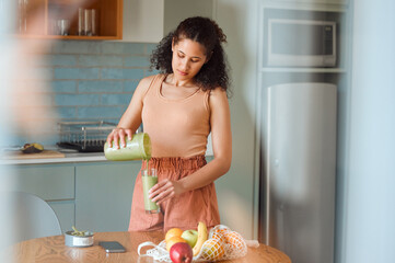 Healthy, nutrition and wellness smoothie made by young woman for her fresh, green detox or vegan...
