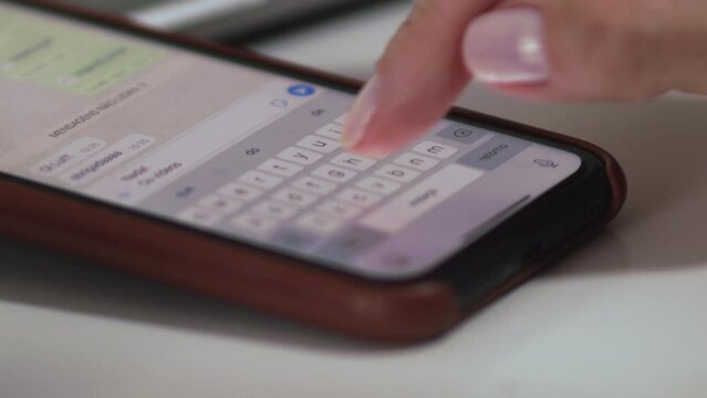 Close up, unrecognizable person using fingers to type message in Whatsapp on iPhone