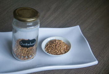 Raw Buckwheat in white ceramic bowl on wooden wood