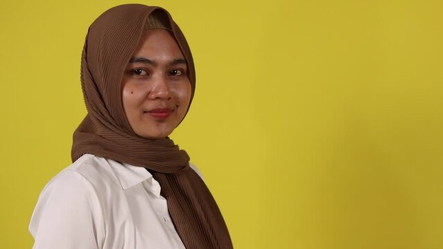 Fashion portrait of young beautiful asian muslim woman with wearing hijab isolated on yellow background