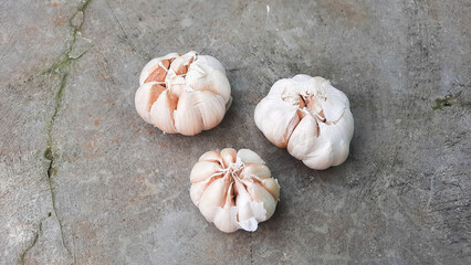 Three cloves of garlic with exposed cement background