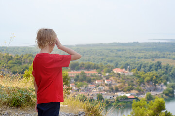 Little child tourist visiting famous fortress Rozafa near Shkodra city. Boy admiring view of valey...