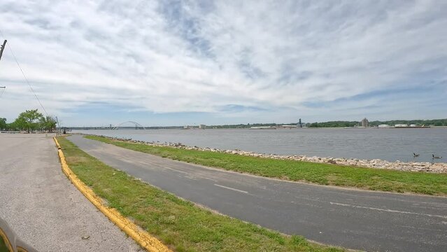 POV Driving Slowly Along The Great River Trail Oir Hiking And Biking;  Along The Banks Of  Mississippi River; Driving Towards The Arches Of The Iowa-Illinois Memorial Bridge