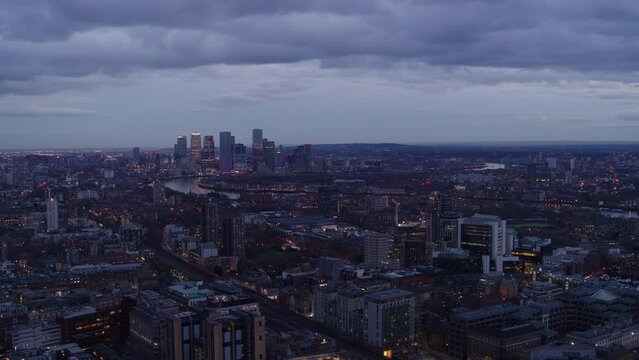 Rising aerial establishing shot over the Limehouse district at dusk. River Thames and Canary Wharf seen in the distance.