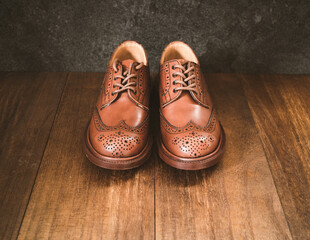 ウィングチップのシューズ、木目の背景