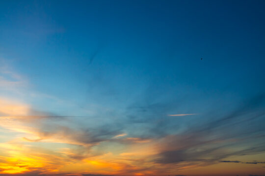 The sky at sunset or sunrise with orange clouds and a blue tint