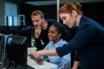 Colleagues discuss work. African young woman, caucasian and red-haired caucasian communicate in the office. 