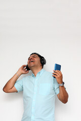 Naklejka premium Latin adult man uses his wireless headphones and cell phone to listen to music, dance, relax and enjoy technology 