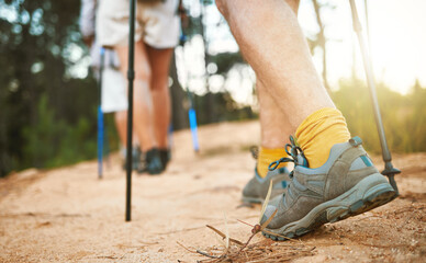 . Feet or shoes walking, trekking and hiking on a trail up a mountain with sticks and poles....