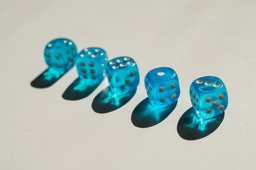 Five transparent blue dice on a white table. 