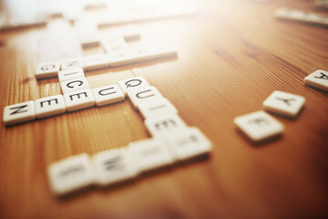 Scrabble, board games and fun with pieces on a table making words, text and language while playing...