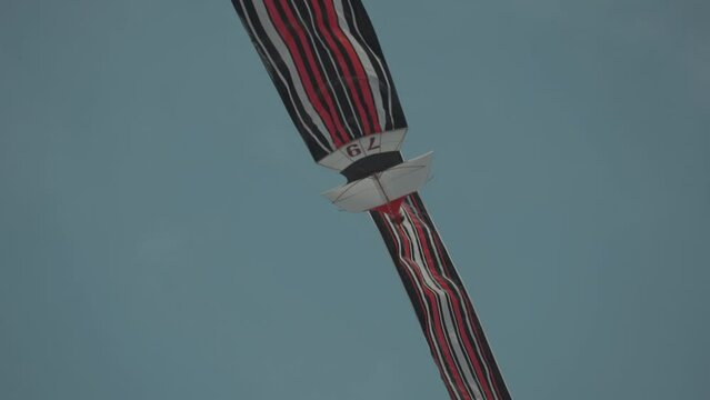 Balinese Traditional Kites JANGGAN (Red White Black Long Tail Bird Dragon) on Bali Kite Festival Summer Blue Sky Slow Motion