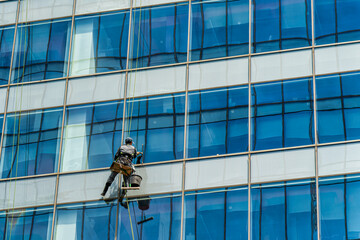 Industrial climber cleaning windows on the facade of an office building.