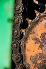 Old oiled chain with a rusty industrial sprocket on a farm harvester