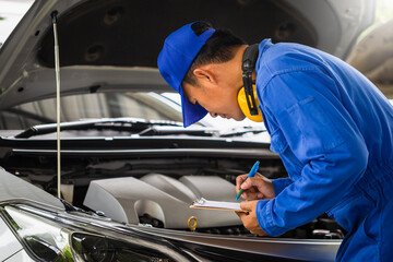 Auto mechanic holding clipboard checklist the car at mechanic shop, Mockup blank clipboard, Technician doing the checklist for repair machine a car in the garage