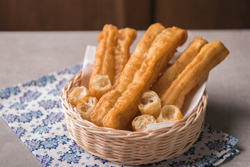 Fototapeta na wymiar Cakwe or You tiao is a long golden-brown deep-fried strip of dough or typical chinese doughnut. Served in bamboo woven plate