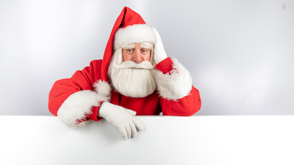 Santa Claus peeks out from behind an ad on a white background. Merry Christmas.